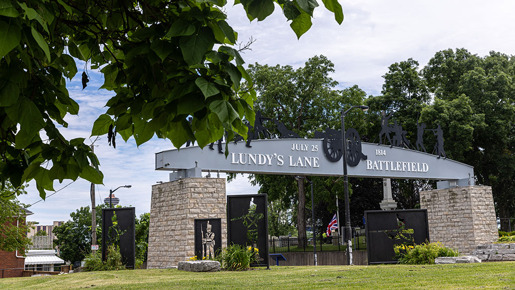 Image of the Lundy's Lane Battlefield archway. With black metal artwork of soldiers and a cannon.