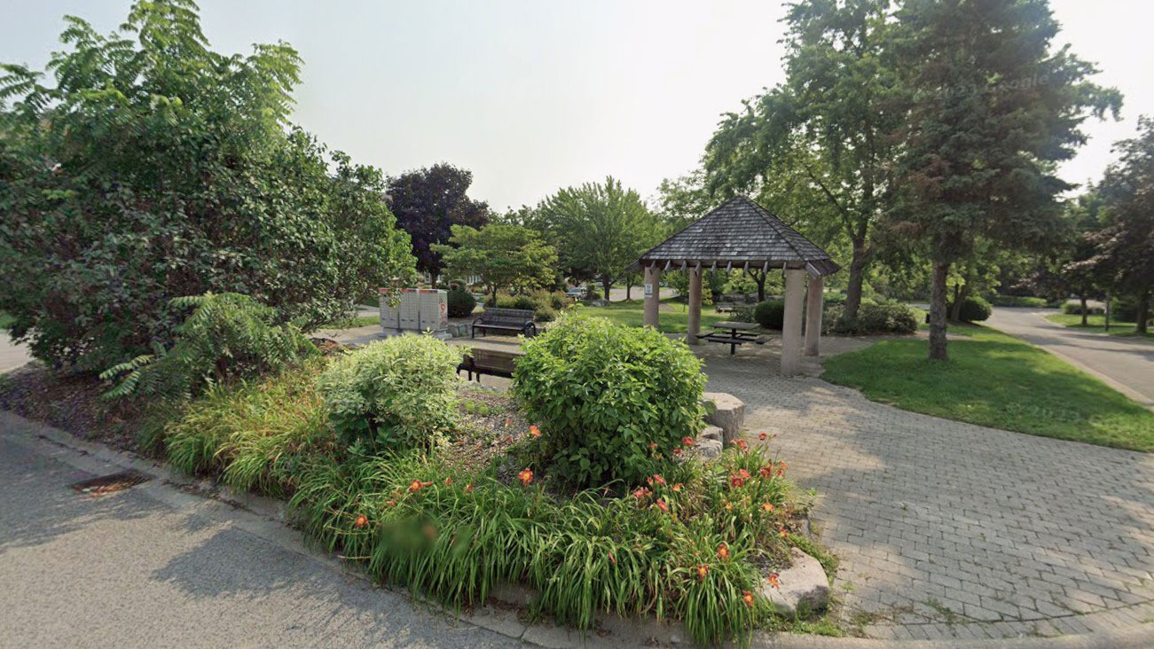 Street image of Stonefield Park in the summer. Showing green landspcaping, benches, and a sheltered pavilion.