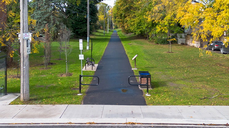 NS&T Trail at Drummond Road entrance. Showing the newly paved asphalt on the trail and green grass on either side of the trail.