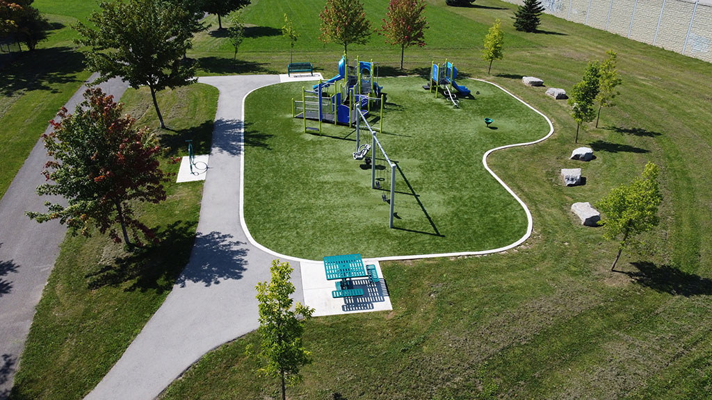 Drone overhead photo of CB Wright Park playground, paved walking path, picnic table and grassy area.