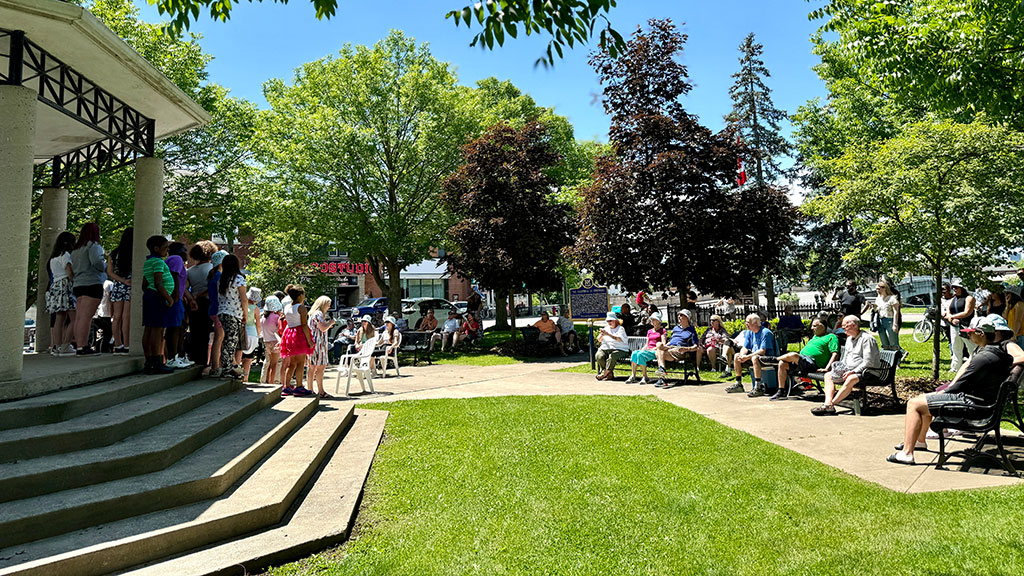Cummington Square showing the raised gazebo stage and people enjoying a live performance by school children.